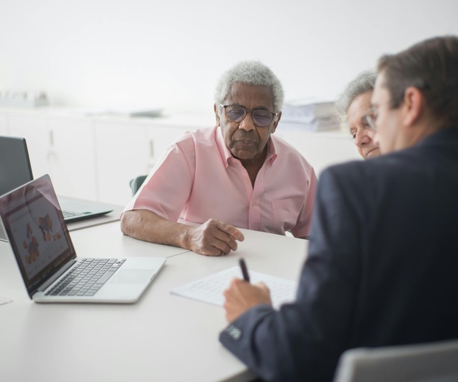 Advisor sitting with senior client and adult child reviewing insurance options